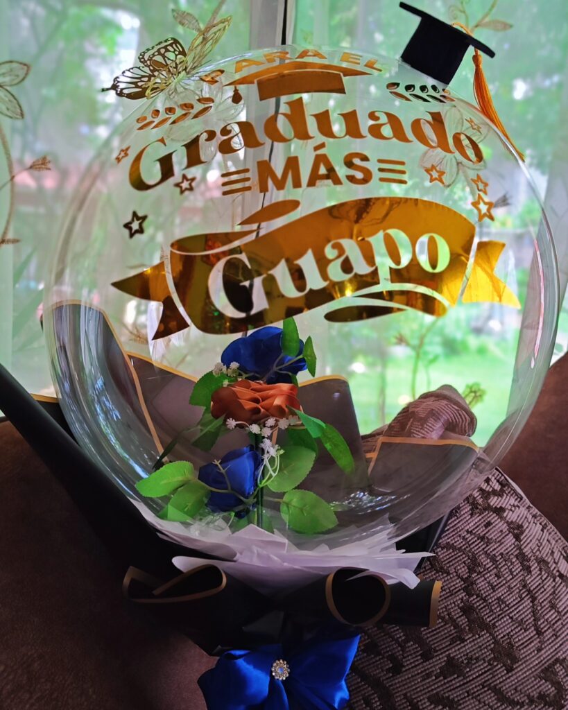 Arreglo de graduación con globos metálicos, birrete y mensaje personalizado.