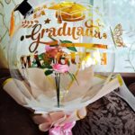 Globo de graduación con frase personalizada y rosas eternas en vinil dorado.