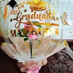 Globo de graduación con frase personalizada y rosas eternas en vinil dorado.